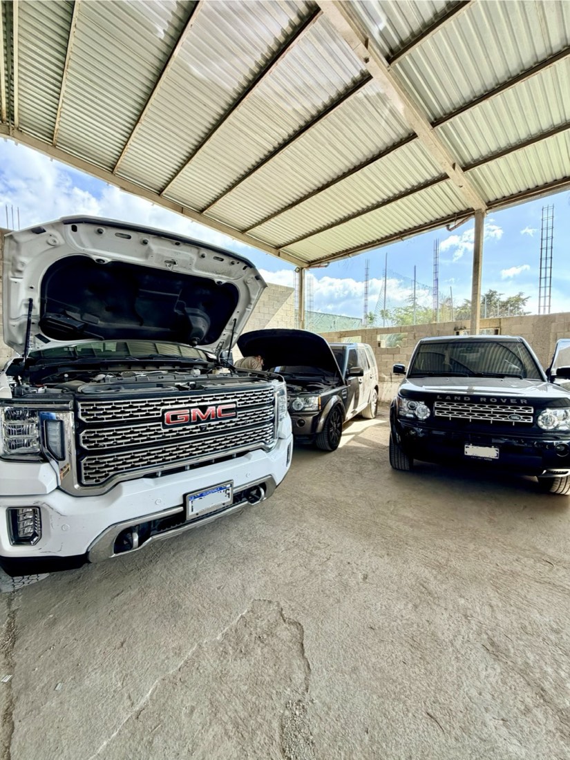 Camioneta GMC y Land Rovers con el capó abierto en el centro de servicio