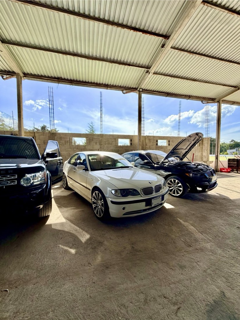 BMW Serie 3 y otros vehículos estacionados en el taller